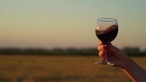 Close up. Slow motion. Glass of red wine in hand of girl against a sunset. Stock Footage 135542884
