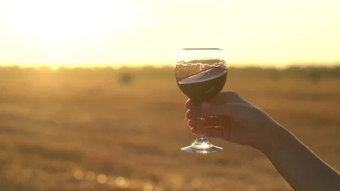 Close up. Slow motion. Glass of red wine in hand of girl against a sunset. Stock Footage 135542923