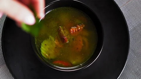 Close-up, Slow Motion, Hand Cooks Top Of Parsley Leaves in Vegan Soup in Black Stock Footage 127472374