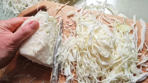 Close-up slow motion of hands slicing fresh cabbage on a wooden cutting board Stock Footage 341934890