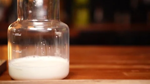 Close up slow motion on jar of milk and small black coffee cup on wooden board Stock Footage 104372268