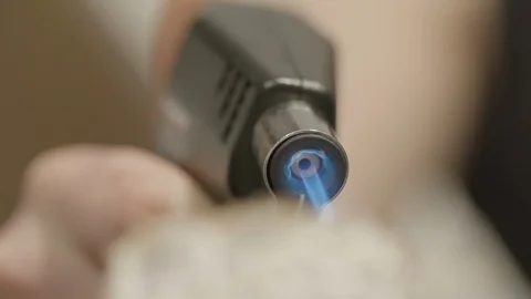 Close-up slow motion lockdown shot of woman caramelizing cheese with butane Stock Footage 129204058