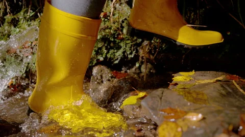 CLOSE UP, SLOW MOTION, LOW ANGLE VIEW: Yellow rain boots walk along forest brook Stock Footage 342357011