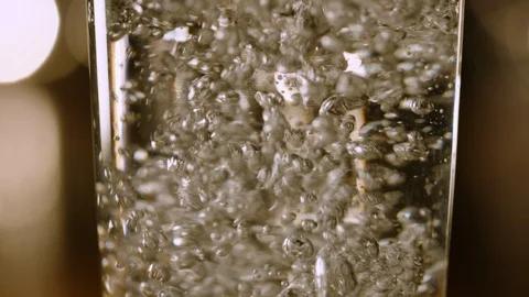 Close Up Slow Motion Macro Filling a Glass with Water with Swirling Bubbles Video stock 129396038