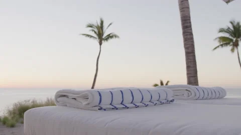 Close up slow motion panning on towels on lawn chairs on beach at sunrise Vidéo 204017552