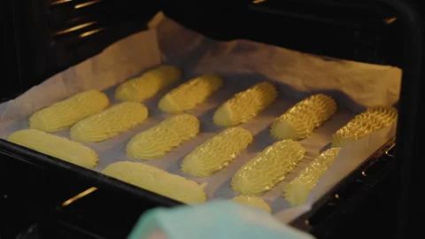 Close-up, Slow Motion, Pastry In Gloves Puts Eclairs in Oven for Baking Stock Footage 136800320