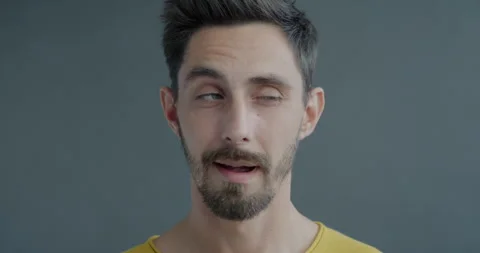 Close-up slow motion portrait of playful guy looking around then winking at Stock Footage 254226979