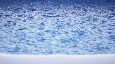 Close up slow motion of rain falling into blue swimming pool Stock Footage 77134321
