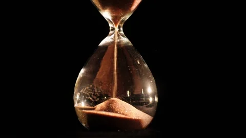 Close up slow motion of sand flowing through an hourglass, symbolizing the .. Stock Footage 334704281