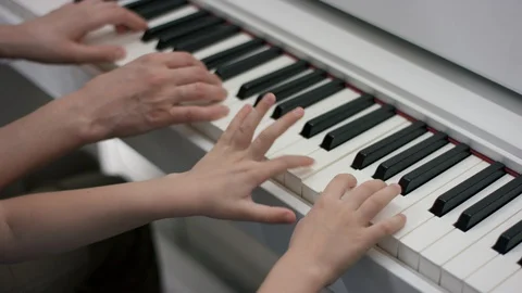 A close up slow motion shooting of hands of an adult and a kid playing music on Video stock 129523262