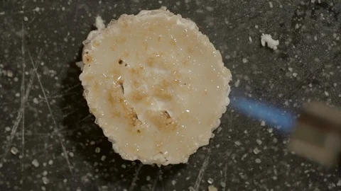 Close-up slow motion shot of caramelizing goat cheese slice with blowtorch on Stock Footage 129205326