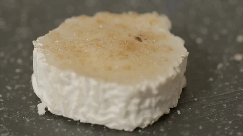 Close-up slow motion shot of caramelizing goat cheese slice on counter in Stock Footage 129207045