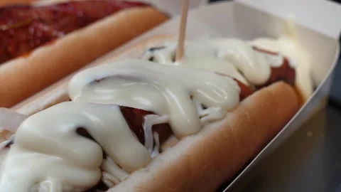 Close-up Slow Motion Shot of a Delicious Hot Dog Being Covered With Creamy Sauce Stockbeeldmateriaal 331955618