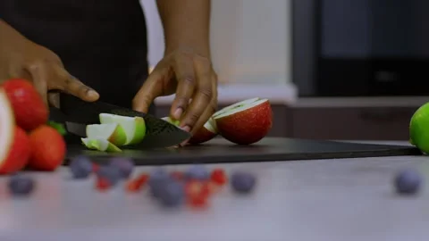 Close-up slow-motion shot of hands holding a knife and cutting an apple into Видео 269893368