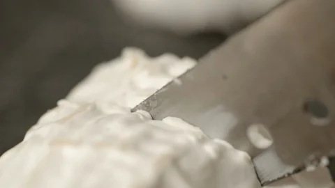 Close-up slow motion shot of knife slicing fresh goat cheese log in kitchen - Stock Footage 129210029