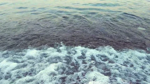 Close up, slow motion shot of the low waves on a rocky beach Stock Footage 189824833