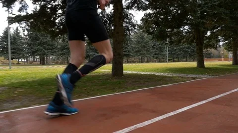 Close-up slow motion shot of a man legs jogging on the course track Stock Footage 74597565