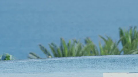 Close up slow motion shot of pool water with view of ocean and palm trees Stock Footage 211444558