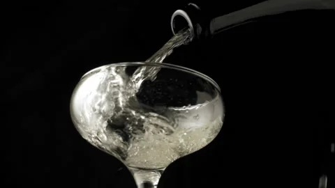 Close-up, slow motion shot: Pouring champagne into a glass on a black background Stockbeeldmateriaal 149835925