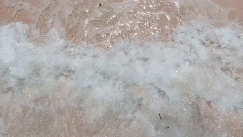 Close-up slow motion shot of sea waves breaking on sandy coastline. Top down Video stock 135218253
