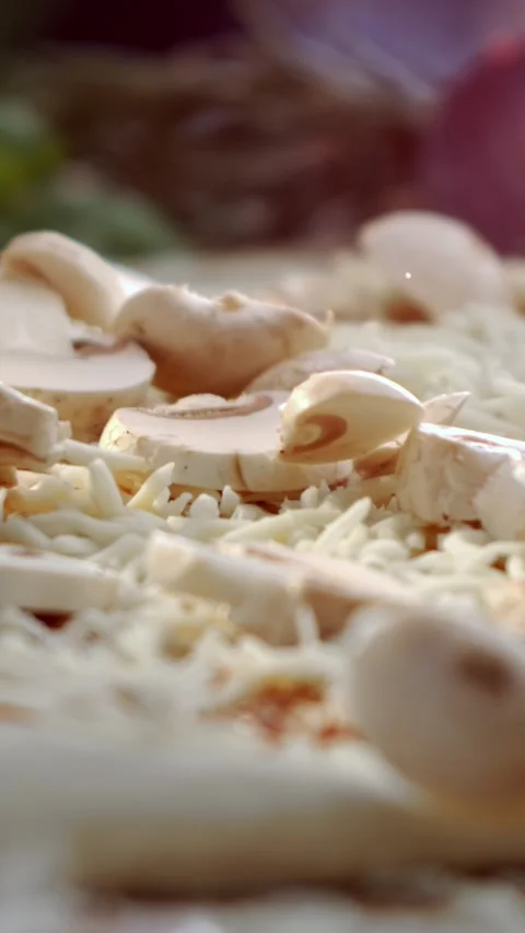 Close-up slow motion shot of sliced button mushrooms falling onto a pizza b.. Stock Footage 337384861