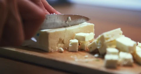 Close up slow motion shot, slicing feta cheese with knife, woman hands, 4K. Stock Footage 120234571