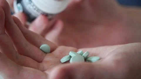 Close-up slow motion shot of white pills being poured into a hand Stock Footage 317049109
