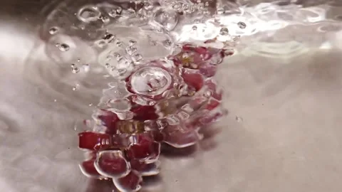 Close up slow motion of small red grapes falling into stainless steel sink wi Stock Footage 144973354