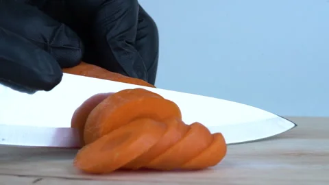 Close up slow-motion, sweeping some carrots on the chipping block by knife, Видео 136715678