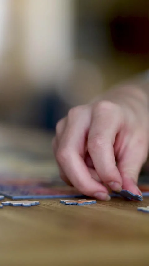 Close-up slow motion vertical view of young woman hands assembling puzzles. 스톡 동영상 305124270