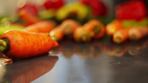 Close-up slow motion video of fresh carrots falling on the table. Stock Footage 296361958