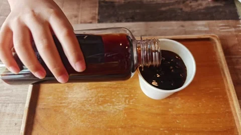 Close up slow motion video of a little child hand carefully pouring black. Stock Footage 340161122