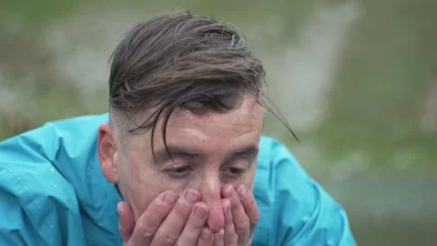 Close-up slow motion video of a man washing his face in a mountain lake. Stock Footage 214326535