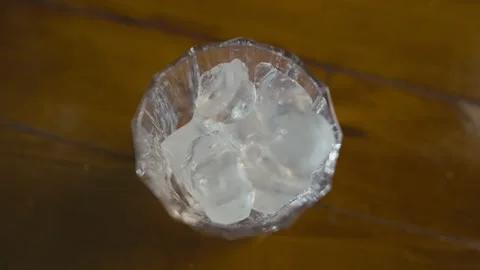 Close-up slow motion video of pouring ice cubes into a glass. Stock Footage 231999536