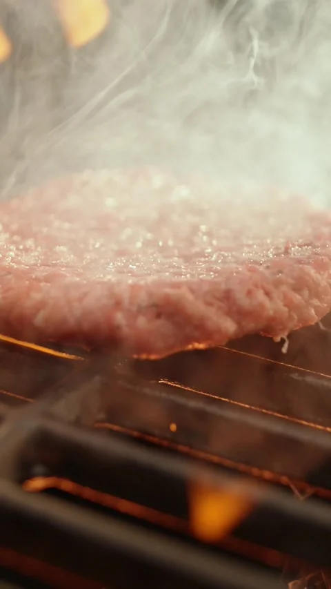 Close up slow motion video of putting a raw burger patty on a hot grill wit.. Stock Footage 337518879