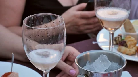 Close-up slow-motion video, a woman's hand throws ice into a glass of champagne Stock Footage 278584375