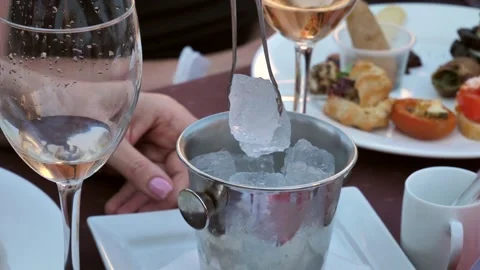 Close-up slow-motion video, a woman's hand throws ice into a glass of champagne Stock Footage 278869284