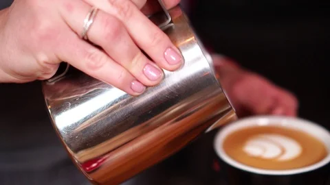 Close up slow motion view on barista coffee maker doing latte art with milk on Stock Footage 104540960