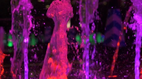 Close-up slow motion view of beautiful colorful fountain on city street at night Stock Footage 97213702
