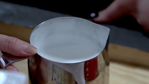 Close up slow motion view of female barista shaking up milk in shiny metal pot Stock Footage 122293237