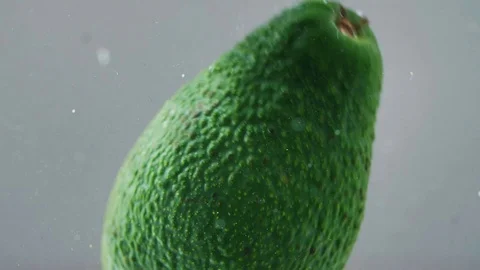 Close up slow motion view of fresh avocado falling and swimming in water Video stock 107380550