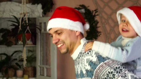 Close up slow motion view on happy smiling father in Xmas Santa Claus hat giving Stock Footage 98659070