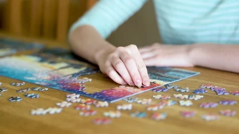 Close-up slow motion view of young woman hands assembling puzzles at home. 스톡 동영상 300766590