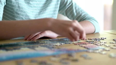 Close-up slow motion view of young woman hands assembling puzzles at home. Stockbeeldmateriaal 302364960