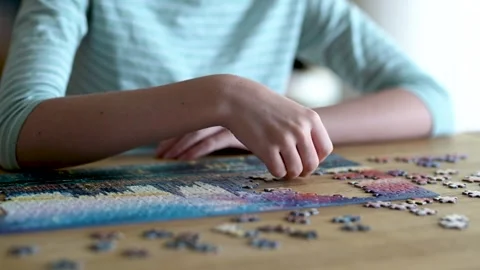 Close-up slow motion view of young woman hands assembling puzzles at home. Stockbeeldmateriaal 304070890