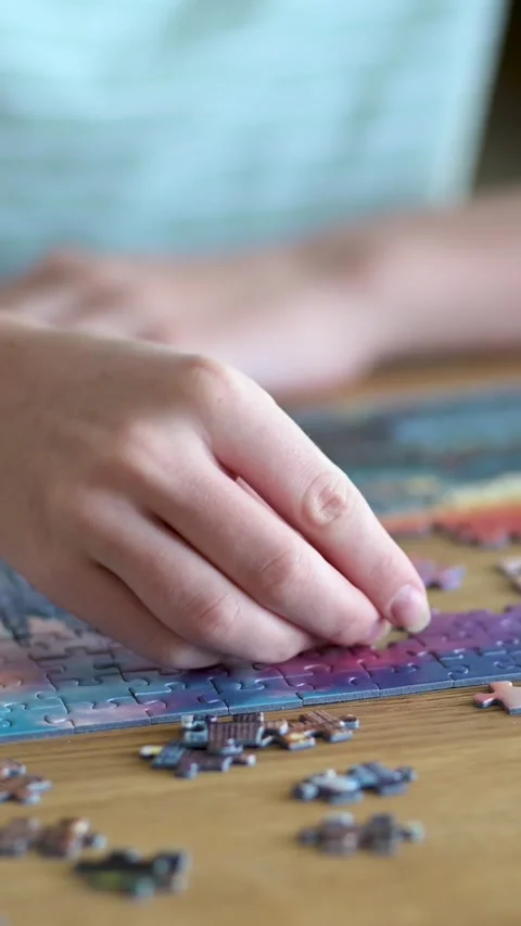 Close-up slow motion view of young woman hands assembling puzzles at home. 스톡 동영상 305410029