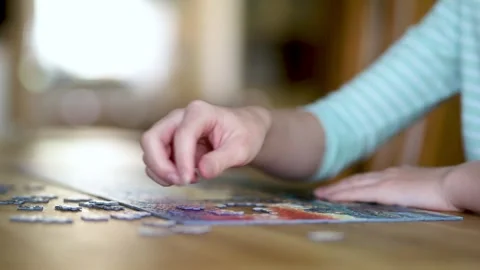 Close-up slow motion view of young woman hands assembling puzzles at home. 스톡 동영상 312150217