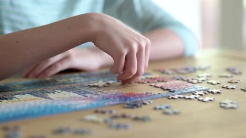 Close-up slow motion view of young woman hands assembling puzzles at home. 스톡 동영상 315143564