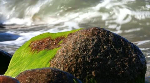 Close up of a slow motion of a wave that crashes against a large rock Stock Footage 11134490