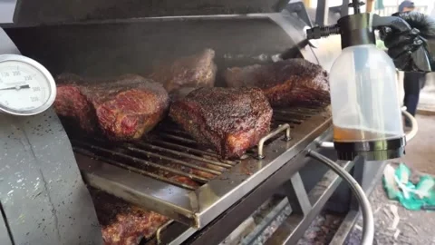Close-up of Slow-Smoked Beef Briskets on an Offset Smoker with Spray Spritzing Stock Footage 338212376